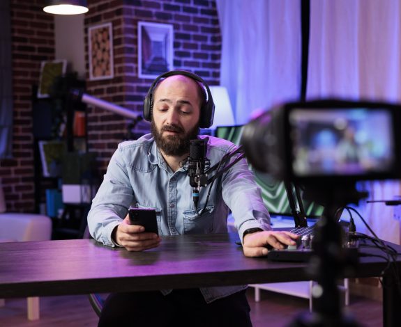 Content creator doing live broadcasting for online streaming service surprised by comments received from followers. Famous vlogger interacting with fans while recording in living room studio