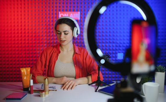 Famous blogger. Cheerful female vlogger is showing cosmetics products while recording video and giving advices for her beauty blog.